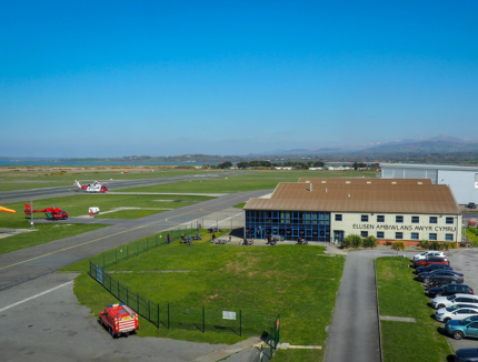 A panoramic photograph of the Caernarfon base with the helicopter on the apron