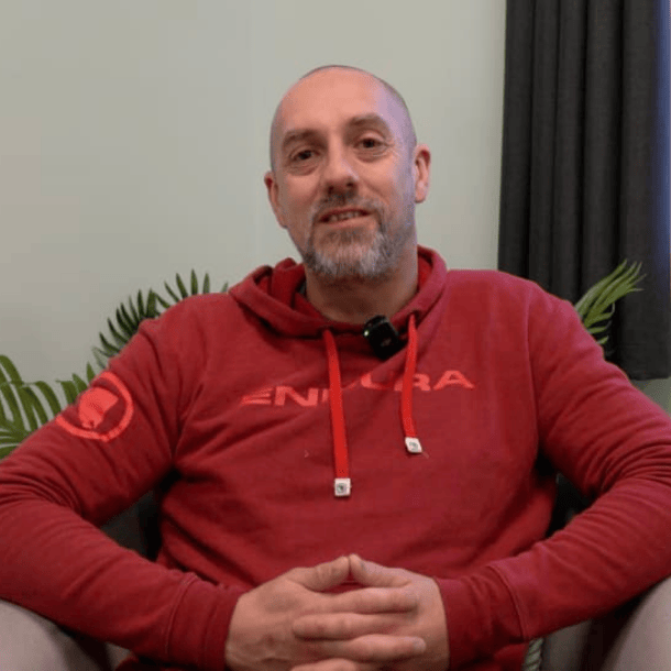 Richard sitting in chair facing camera wearing red jumper