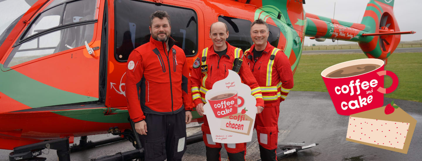 Three members of crew with a promotional board with the branding for a coffee and cake event