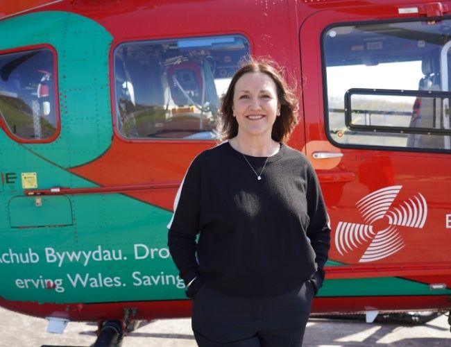 Gail standing in front of helicopter